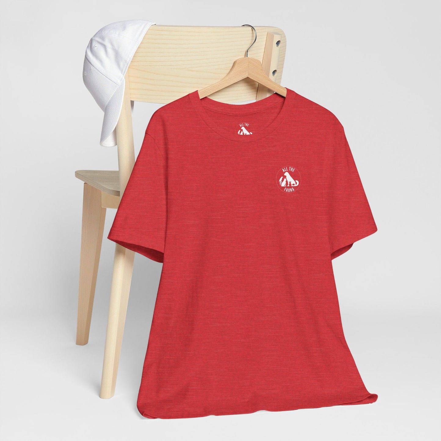 CATS, PERIOD. unisex cat tee front view highlighting minimalist chest logo on soft heather red cotton on wood hanger hanging from chair